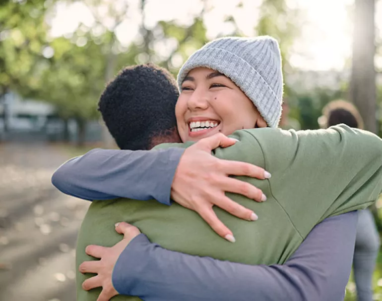 Former homeless teens giving each other a hug outdoors | Covenant House - Donate now
