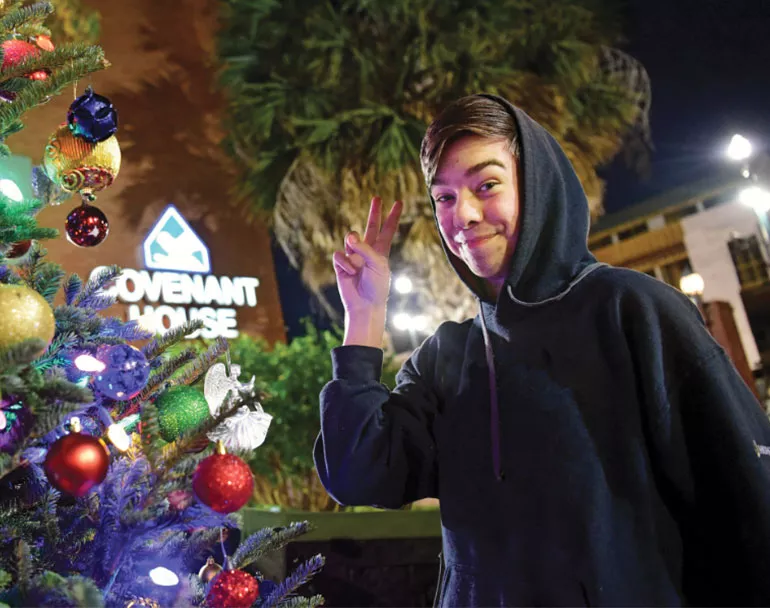 Former homeless teen next to Christmas Tree | Covenant House