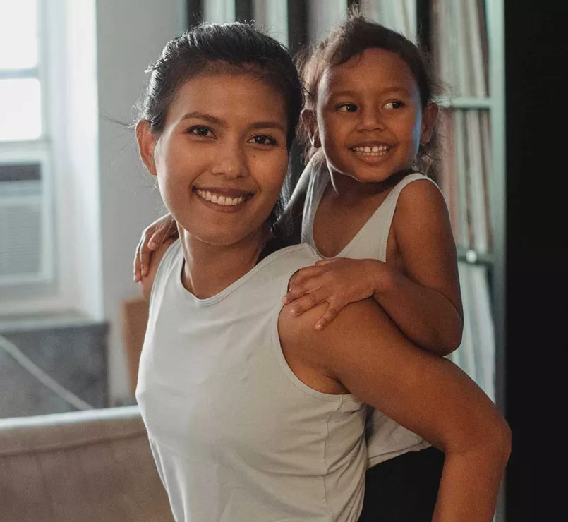 Latin American mom giving child piggyback ride | Covenant House Latin America Family Support Services