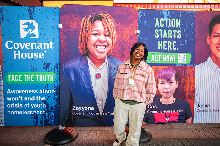 Covenant House homeless youth in front of portrait spreading our mission at Youth Homelessness Awareness Month NYC Times Square Rally