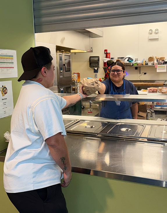 Covenant House Illinois Lead Cook, Ariana Carrera, giving meal to homeless youth