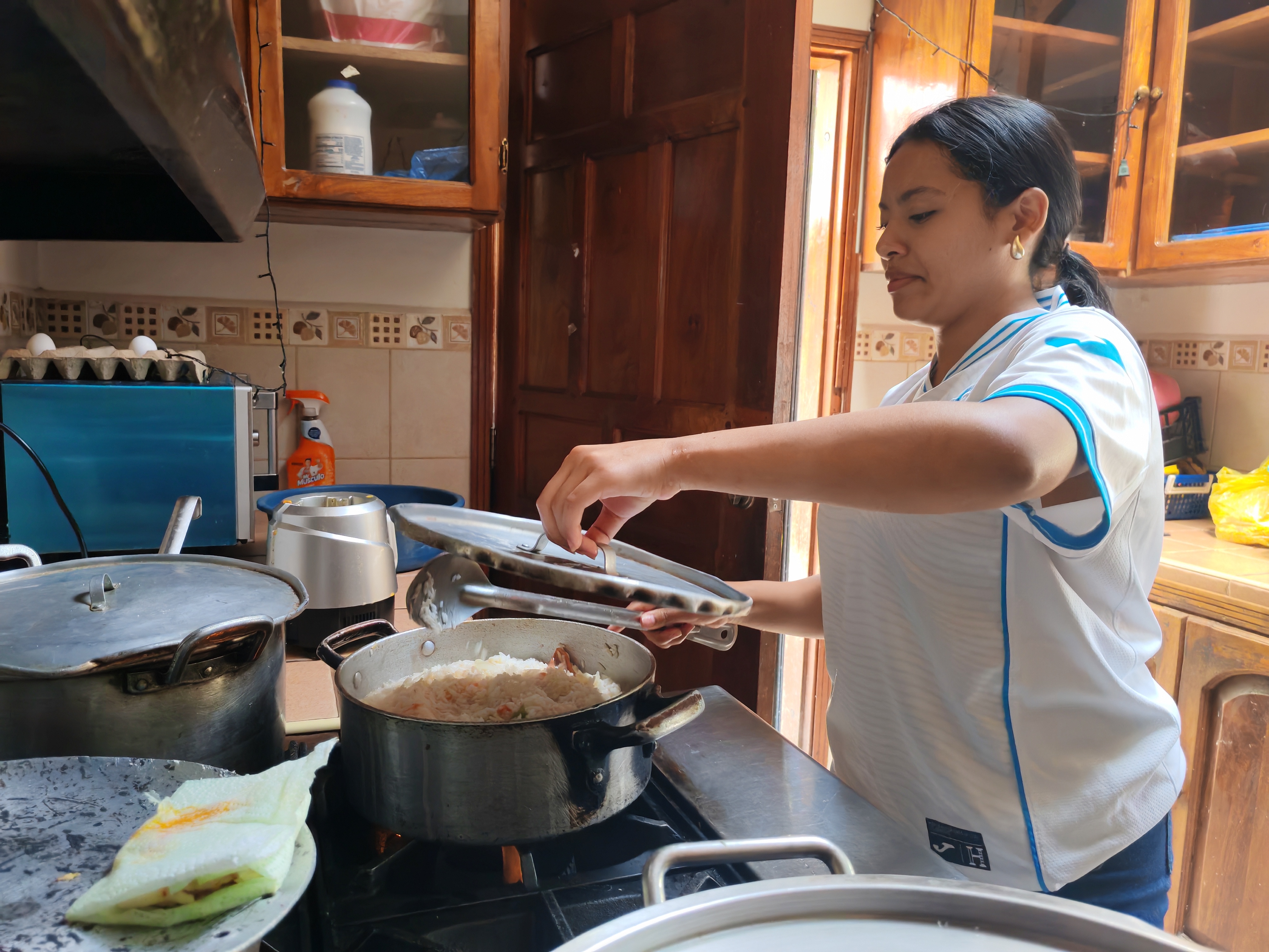 Alma, a former resident of Covenant House Honduras, cooking food in a kitchen.