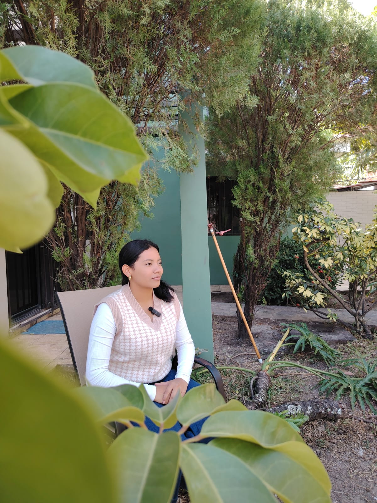 Alma, a former resident of Covenant House Honduras, reflects on her journey while seated in a garden.