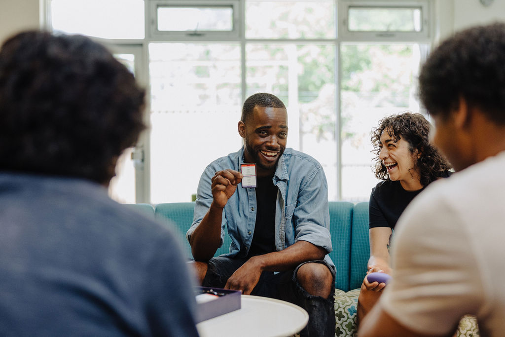 Four individuals laughing and sharing in Covenant House Chicago's Community Room.