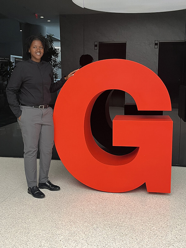 Jasmine standing by a large "G"