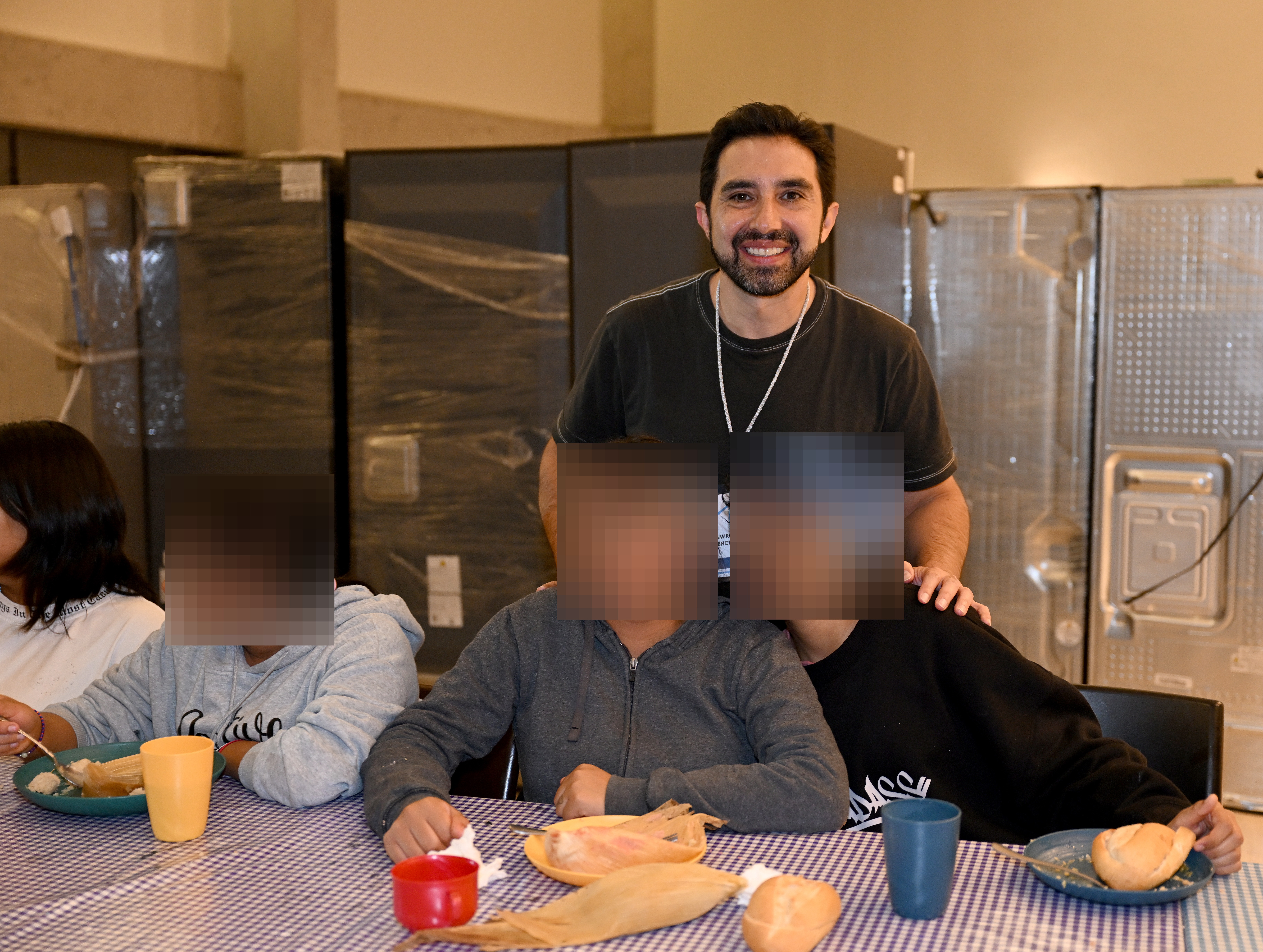 Ramiro Menchaca (standing) poses between two residents (seated at table) at Covenant House Mexico Sleep Out.
