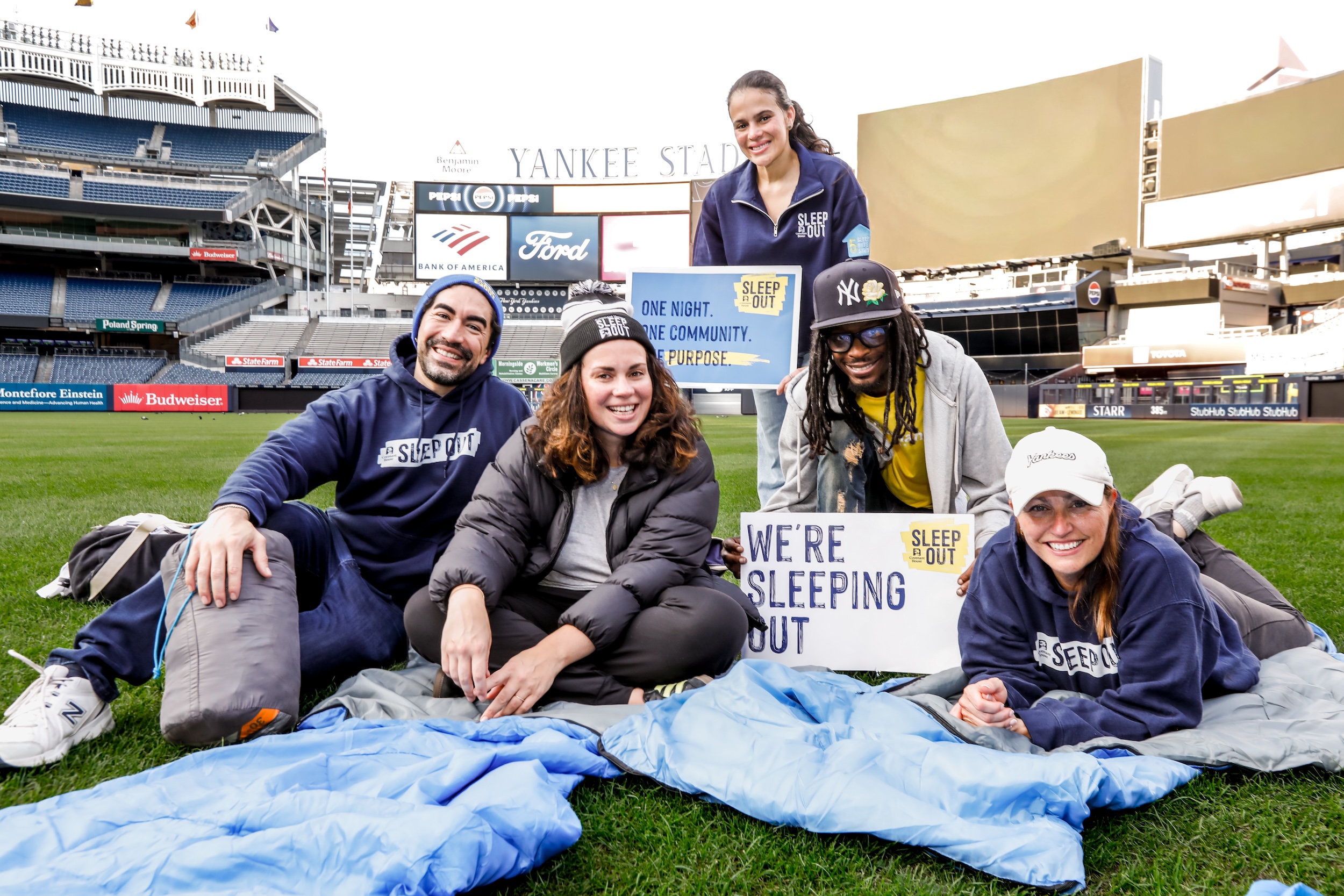 Covenant House International staff with sleeping bags and Sleep Out signs relax on the grass at Yankee Stadium ahead of the 2019 Sleep out there.