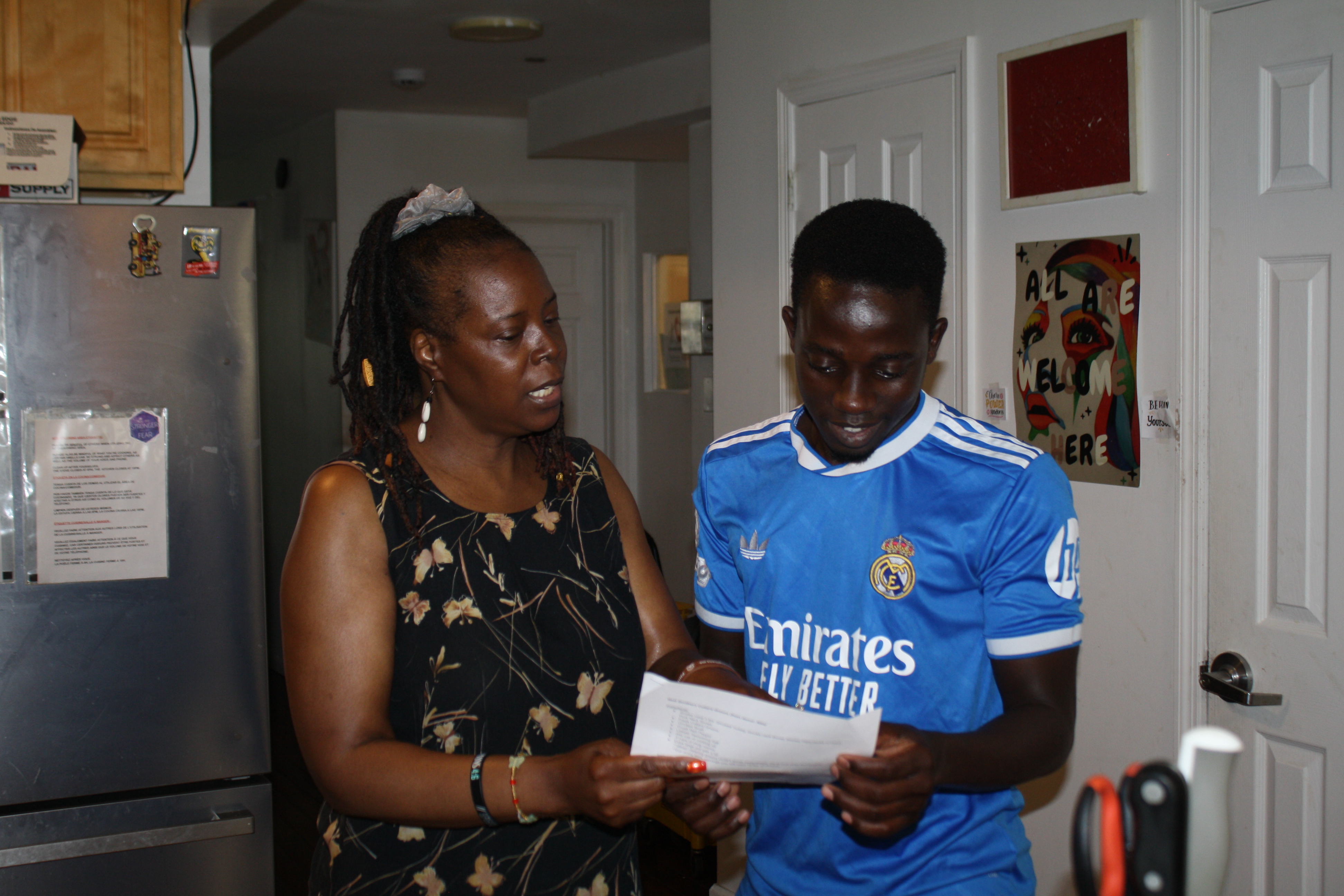 A Covenant House staff member talking a resident through a recipe in the kitchen.