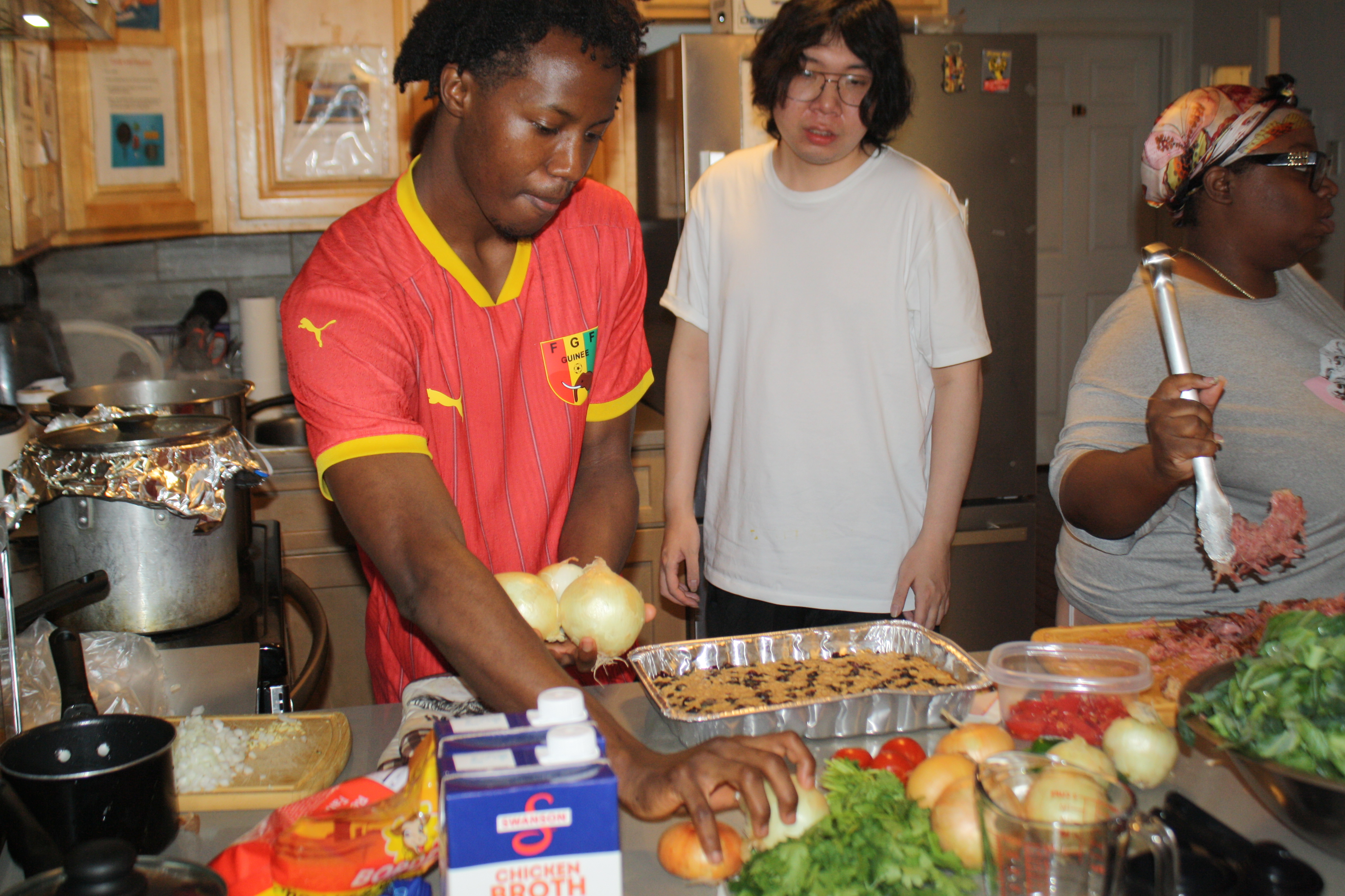 Three Covenant House residents in a shelter kitchen prepping ingredients as they prepare to cook recipes sent to them from supporters.