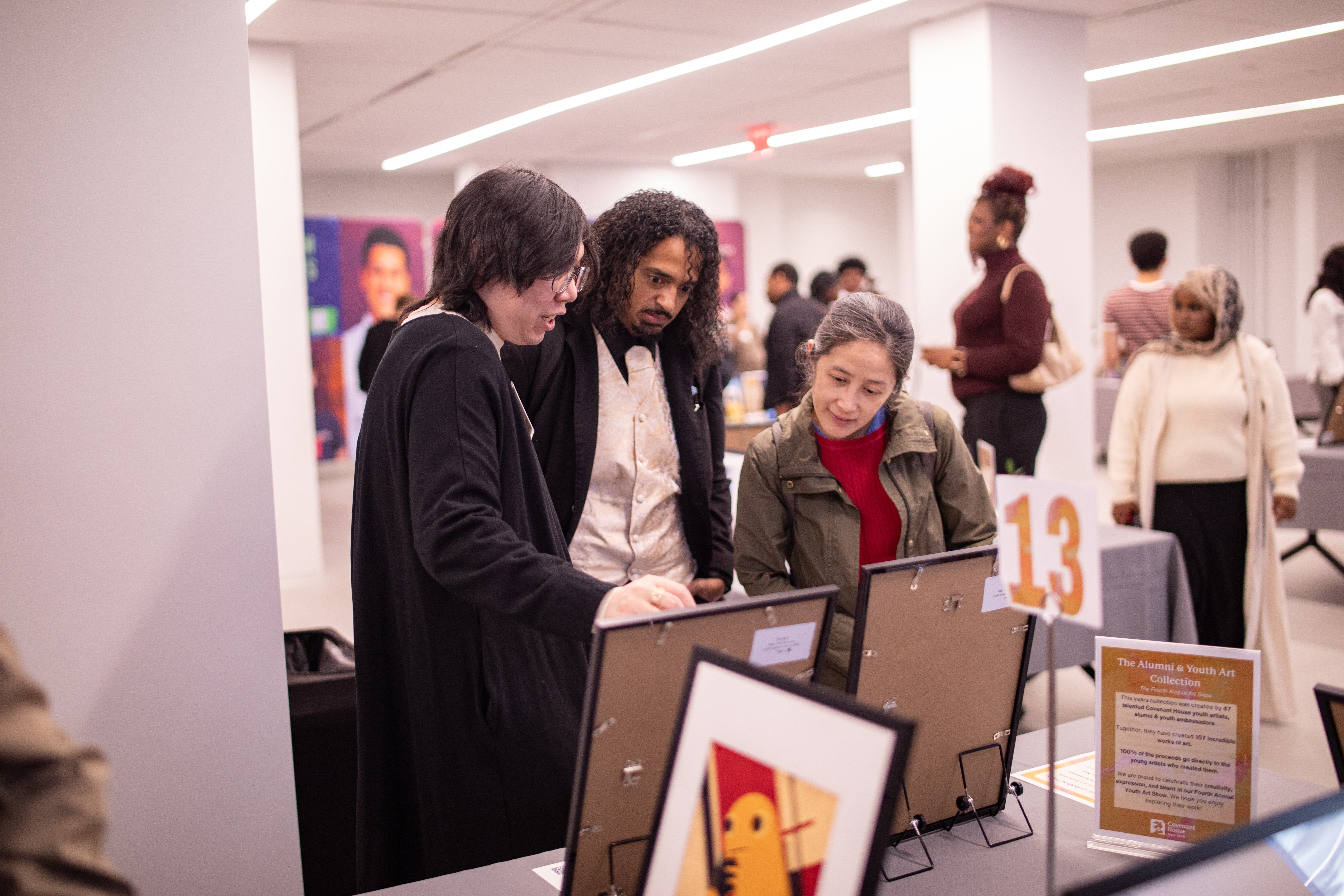 CHNY youth talks with patrons around a table about the works he created at the fourth annual CHNY Youth Art Show.