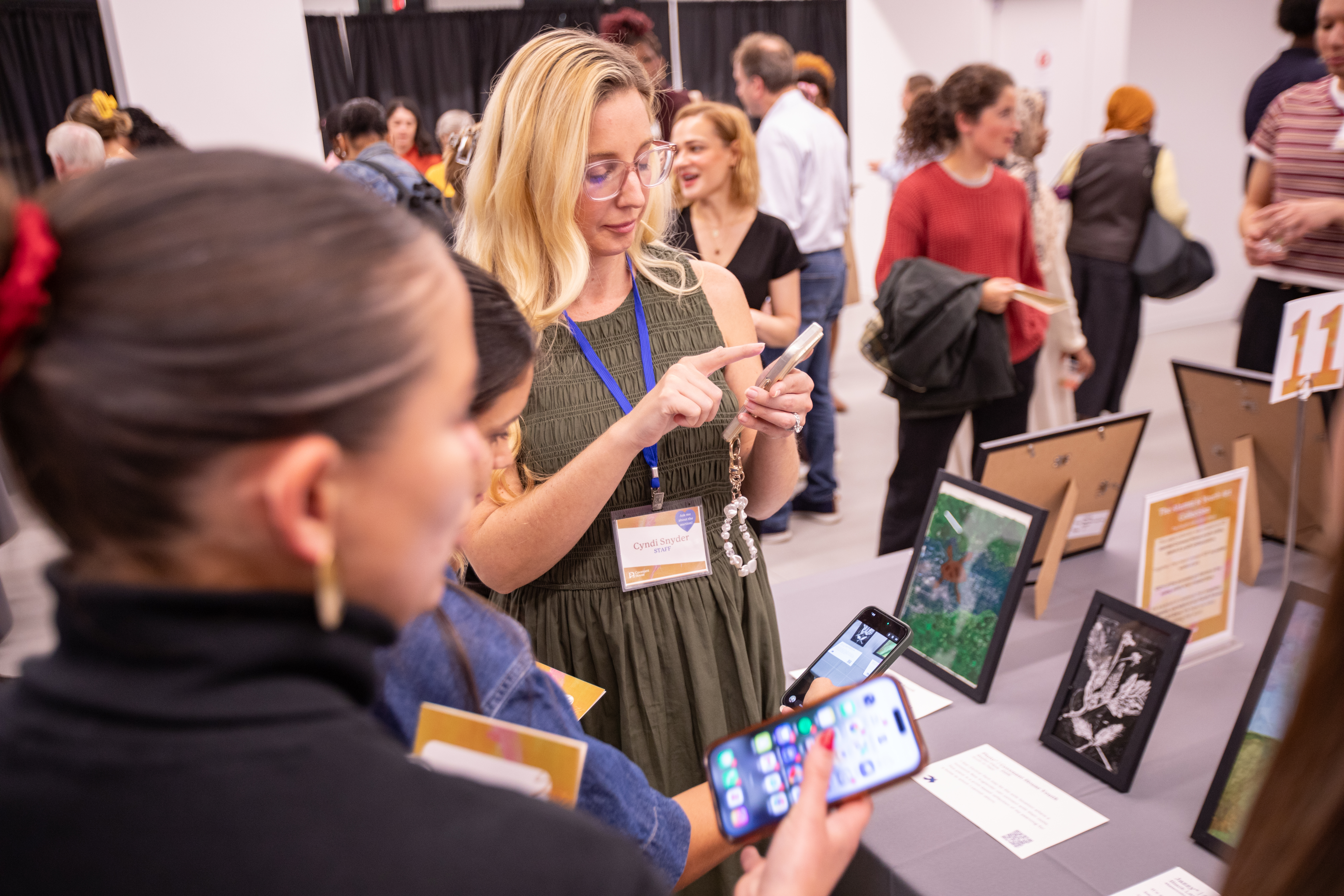 Covenant House staff and patrons check bids on various pieces of art on a table at the CHNY Youth Art Show.