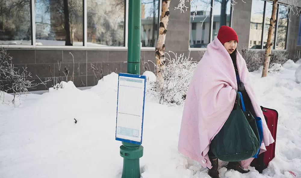 homeless girl outside with blanket and suitcase during the winter | Covenant House