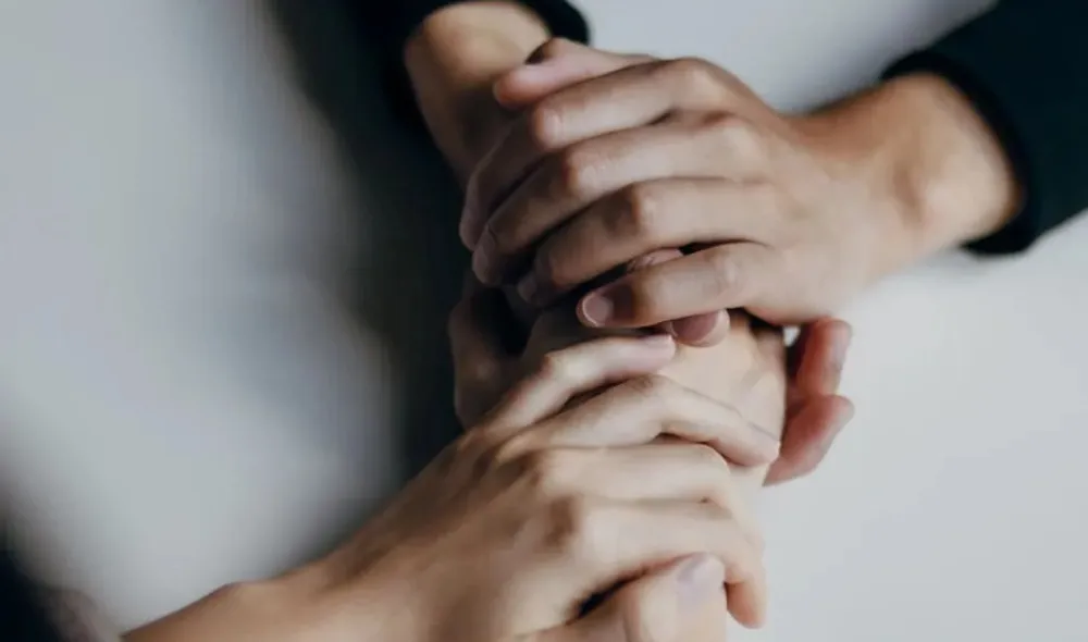 Two people holding hands consoling each other.