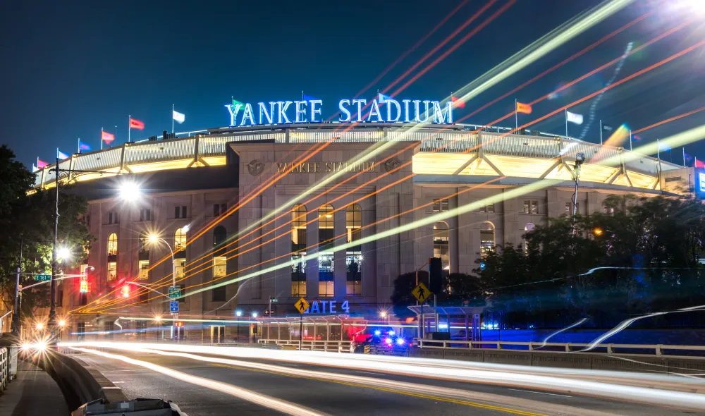 A nighttime, time-lapse, wide-shot photo of Yankee Stadium.