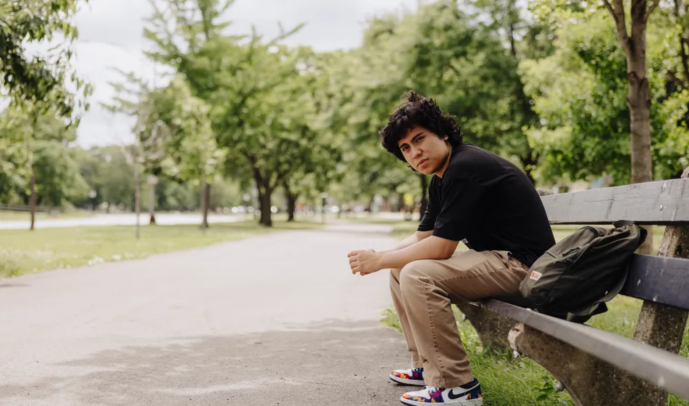 Lost youth sitting alone on a park bench in Chicago during the day.