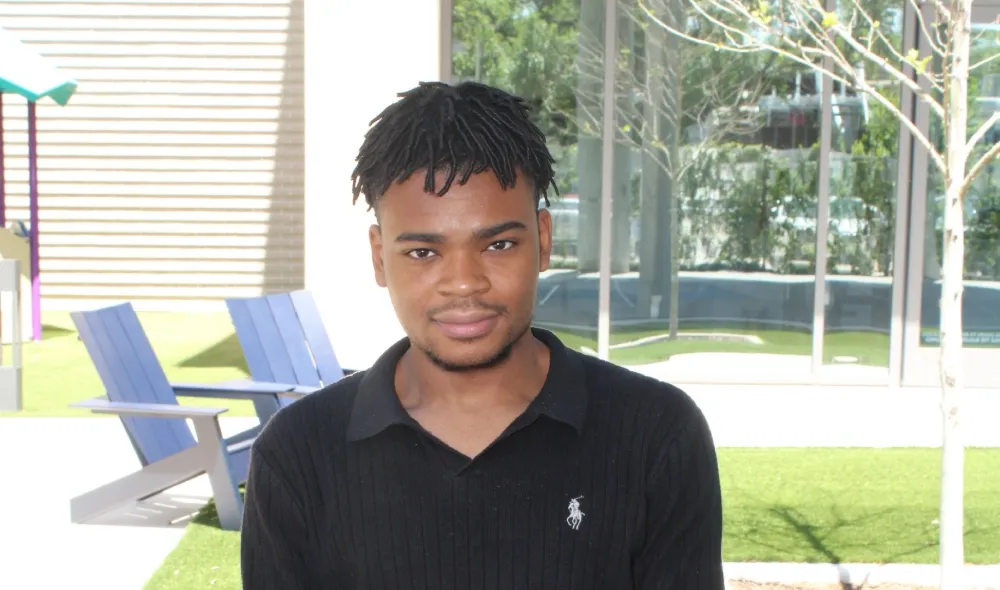 Prince from Covenant House Texas poses outside in a courtyard.