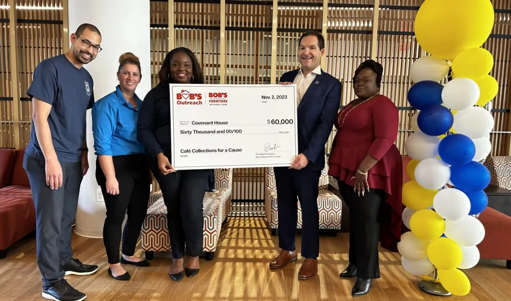 Executive for Bob's Furniture hands a large $60,000 check to members of Covenant House.