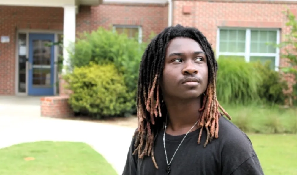 Anyaris, a resident of Covenant House Georgia, looks over his shoulder while posing outside of transitional housing of which he lives while attending school.