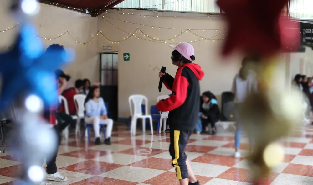 Covenant House Guatemala resident Lucy hold microphone and performs for her peers.