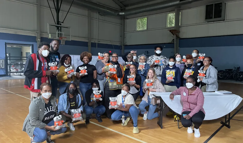 Covenant House Georgia and CHI staff pose with comfort koalas in a gymnasium at the close of a YMHFA course in 2022. The koala is a nod to Australia, where YMHFA originated.
