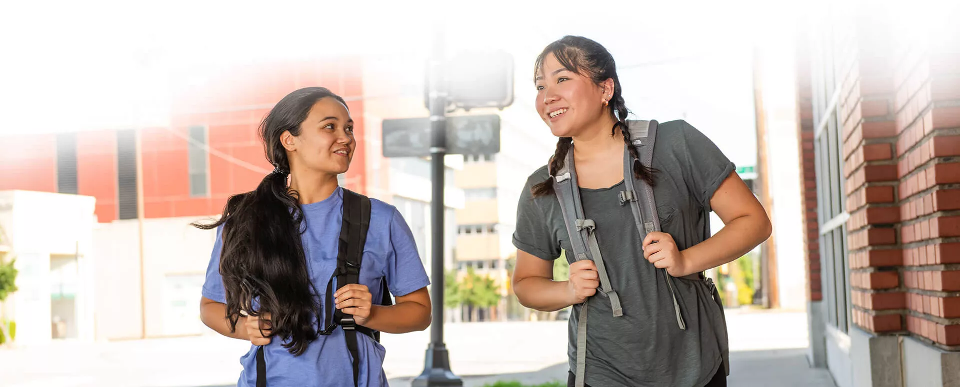 Two young ladies with backpacks walking and talking.