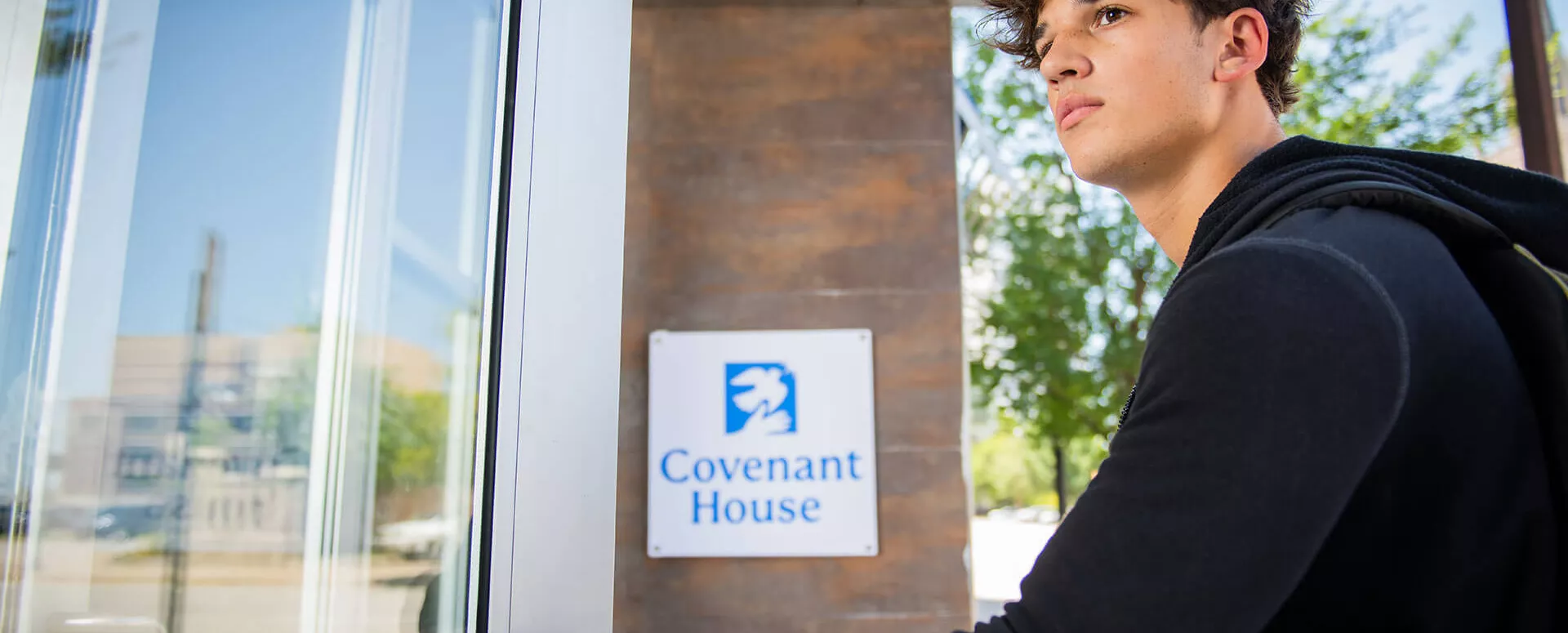 Young man opening a door. Covenant House is open 24/7.