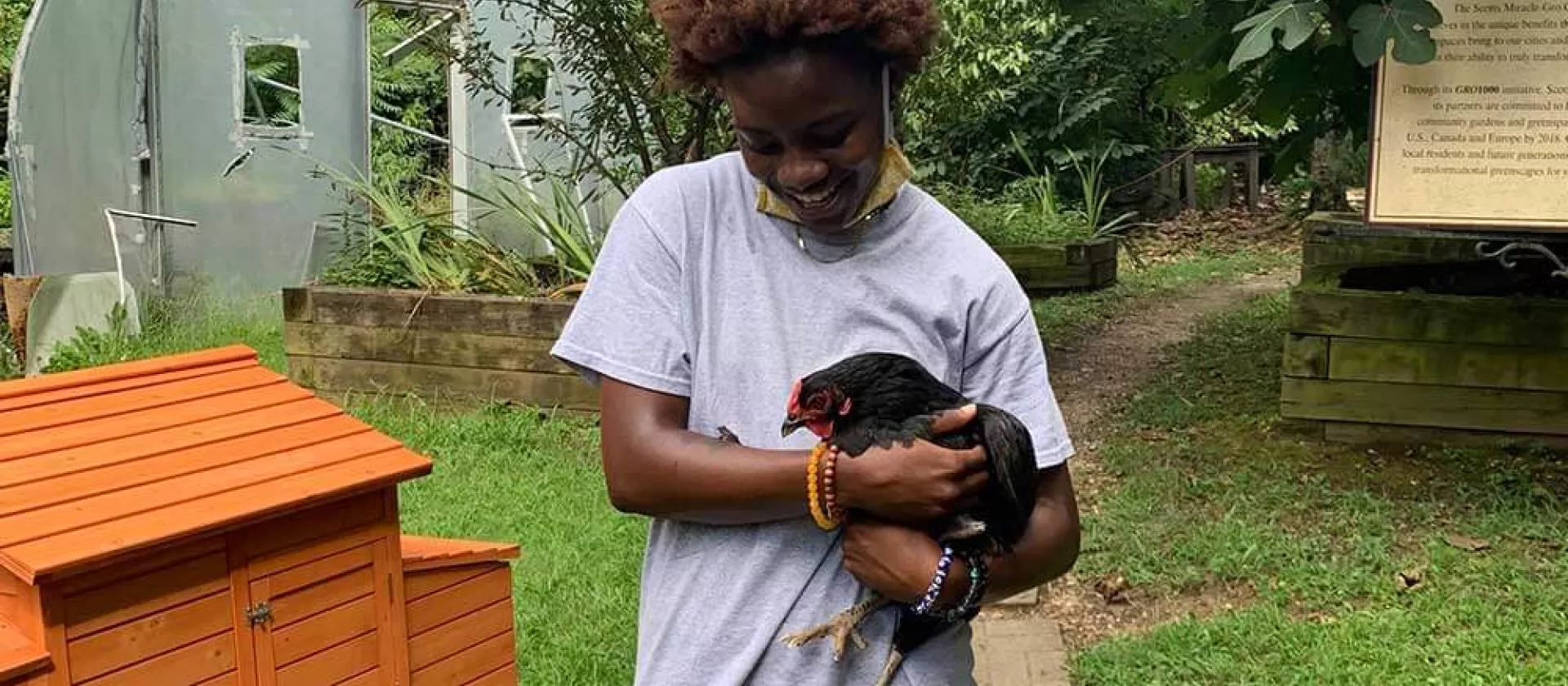 Covenant House resident Ann holding a chicken in a yard