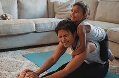 Latin American former homeless mom stretching with child on her back | Covenant House - Latin America
