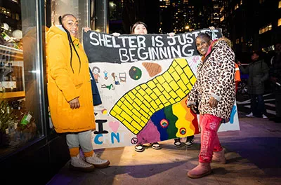 Covenant House Sleep Out volunteers with big art poster saying "Shelter Is Just The Beginning" | Raising funds and awareness for homeless youth