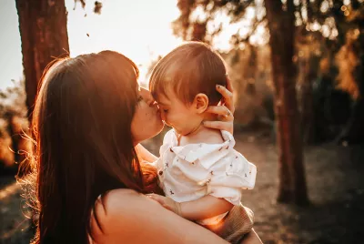 young mother holding and kissing child | Covenant House - Photo by Helena Lopes