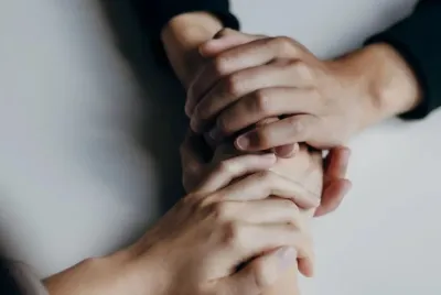 Two people holding hands consoling each other.