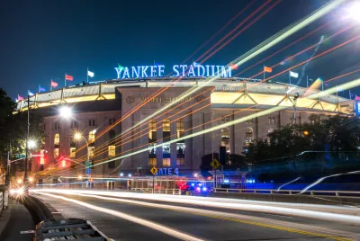 A nighttime, time-lapse, wide-shot photo of Yankee Stadium.