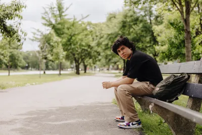 Lost youth sitting alone on a park bench in Chicago during the day.