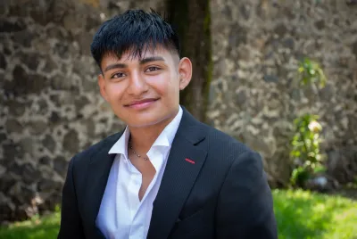 Close-up photo of Edwin at Covenant House Mexico, surrounded by greenery and a stone wall.