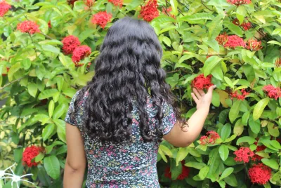 Covenant House Honduras resident Sofia stands, back turned, in a garden of red flowers.