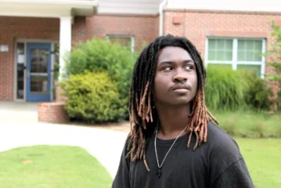 Anyaris, a resident of Covenant House Georgia, looks over his shoulder while posing outside of transitional housing of which he lives while attending school.