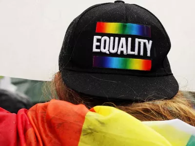 Person at Pride wearing LGBTQ+ flag and equality hat | Covenant House