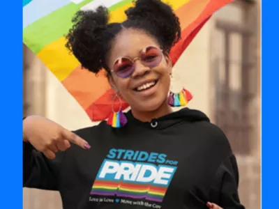 LGBTQ+ youth wearing strides for pride hoodie with LGBTQ+ flag flowing behind