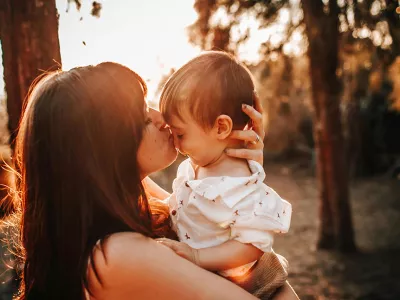 young mother holding and kissing child | Covenant House - Photo by Helena Lopes