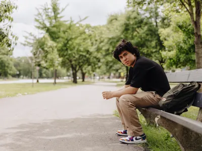 Lost youth sitting alone on a park bench in Chicago during the day.