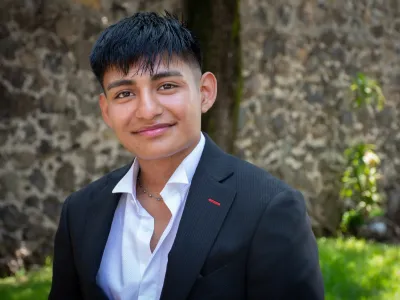 Close-up photo of Edwin at Covenant House Mexico, surrounded by greenery and a stone wall.