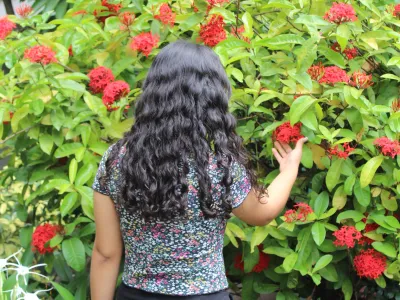 Covenant House Honduras resident Sofia stands, back turned, in a garden of red flowers.