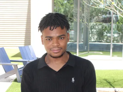 Prince from Covenant House Texas poses outside in a courtyard.