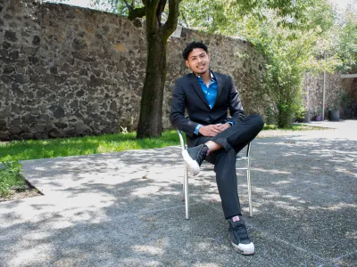 Medium shot of Jonathan, who resides in Covenant House Mexico’s independent living program, posing seated outside in front of a stone wall.