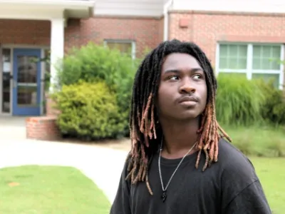Anyaris, a resident of Covenant House Georgia, looks over his shoulder while posing outside of transitional housing of which he lives while attending school.
