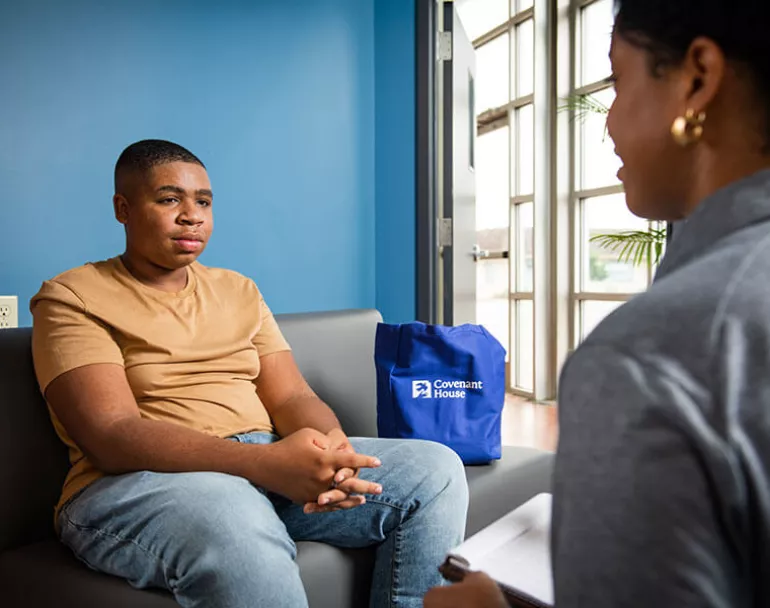Young man sitting and talking to a Covenant House staff