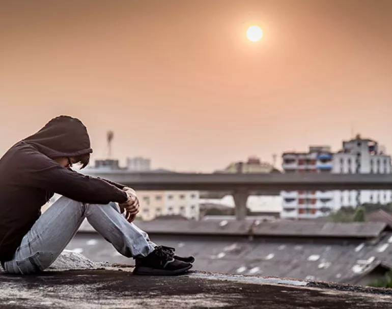 Youth experiencing homelessness and looking at ground 