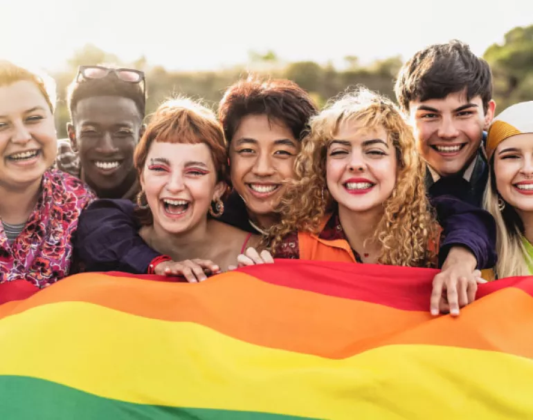 smiling youth holding lgbtq+ flag