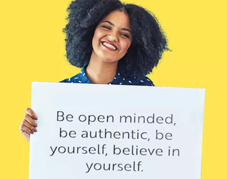 Smiling youth holding sign that reads "Be open minded, be authentic, be yourself, believe in yourself." | Covenant House
