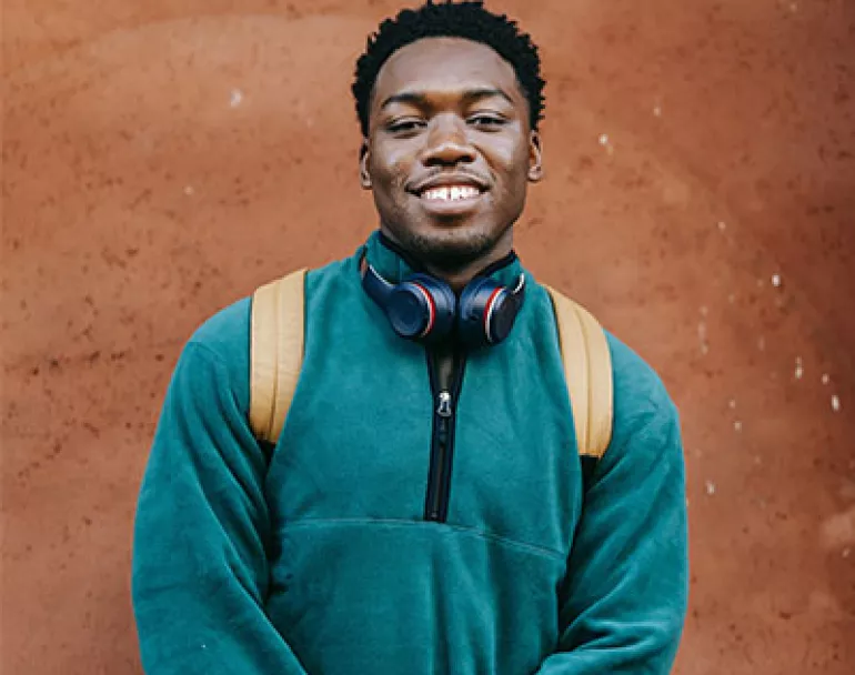 former homeless teen wearing backpack and headphones | Covenant House Donations - Ways to Give